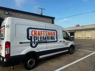A Craftsman Plumbing service van parked outside the company shop building.