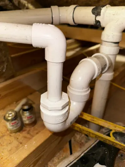 A new PVC P-trap installed beneath a bathroom fixture in an open subfloor space.