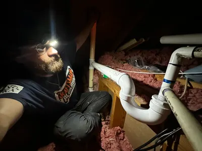Brendan fixing pipes in attic on a residential plumbing job.