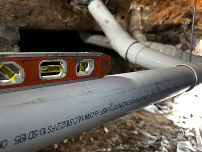 Measure proper pipe fall rate during sewer line work.