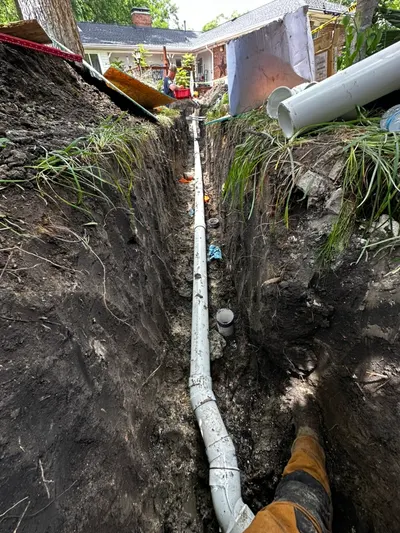 Bury new sewer line in trench during sewer line work.