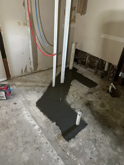Fresh concrete around new pipes during a slab leak repair.