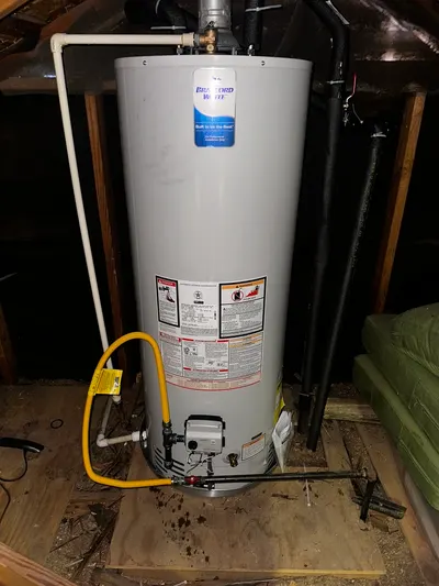A new gas water heater installed in an attic with a flexible yellow gas connector.