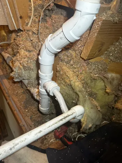 A new PVC pipe run installed through an insulated wall cavity during a repiping job.